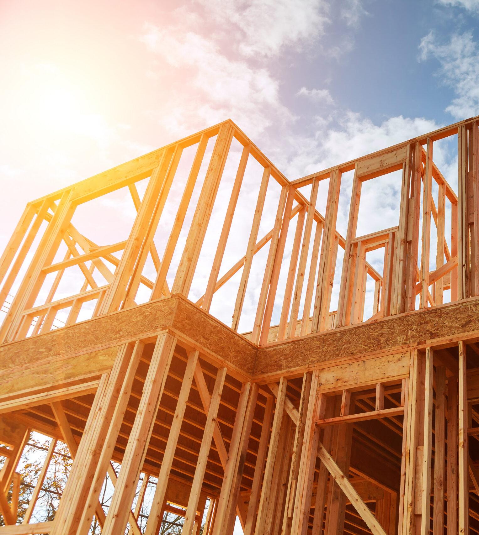 New residential construction home framing against a blue sky.
