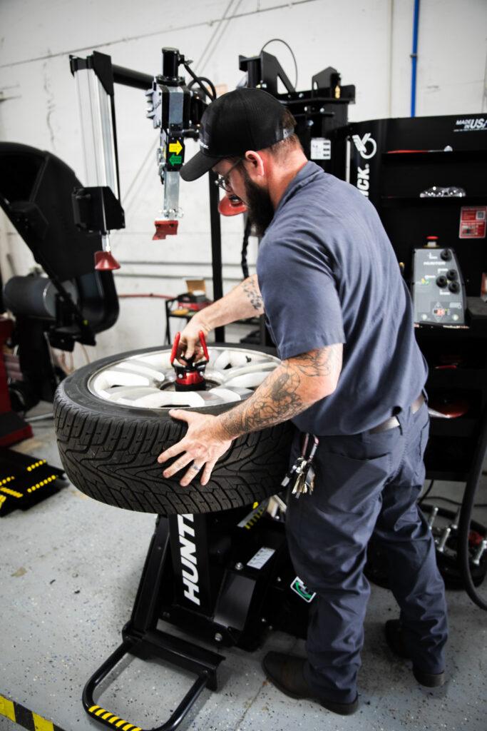 Goodwill Automotive employee works on tire.