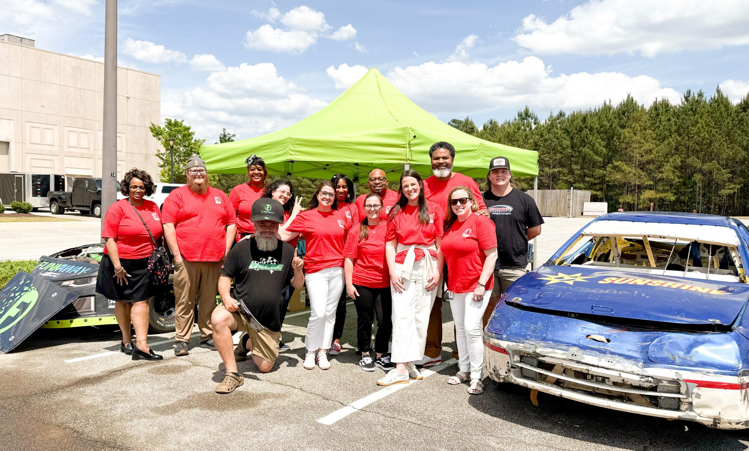 A group of Goodwill employees stand beside a race cars